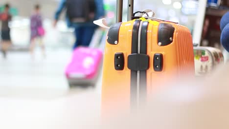 Yellow-Suitcase-safety-bag-in-airport-departure-travel-luggage-for-holiday-vacation-at-blur-airplane-terminal-waiting-area-for-passenger-hall-background,-focus-on-suitcases.