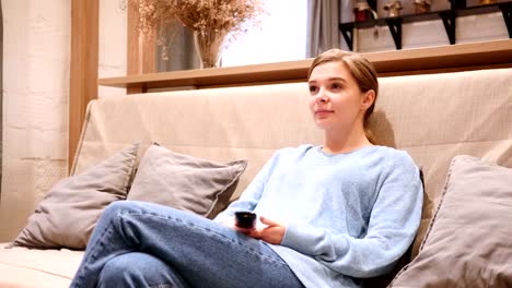 Woman-Watching-TV-and-Changing-Channels,-Sitting-on-Couch