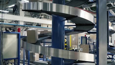 Cardboard-boxes-on-conveyor-belt-in-factory.-Clip.-Production-line-on-which-the-boxes-move-in-a-spiral