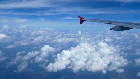 4K-Filmmaterial.-Reisen-mit-dem-Flugzeug.-Blick-durch-ein-Flugzeugfenster.-Flügel-Flugzeug-und-schöne-weiße-Wolken-am-blauen-Himmel-Hintergrund