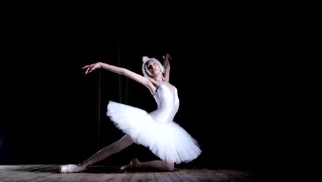 in-rays-of-spotlight,-on-the-stage-of-the-old-theater-hall.-Young-ballerina-in-suit-of-white-swan-and-pointe-shoes,-dances-elegantly-certain-ballet-motion,-Swan-Lake