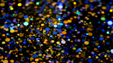 Defokussierten-schillernden-bunten-Glitter-Konfetti,-schwarzer-Hintergrund.-Urlaub-abstrakte-festliche-Bokeh-Lichtpunkte.