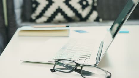 Laptop-With-Eyeglasses-And-Journal-On-Table-At-Home-4K