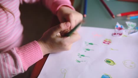 Camera-sliding-left-over-little-Caucasian-preschool-girl-hands-drawing-animals-with-colorful-pencils-at-a-table-close-up