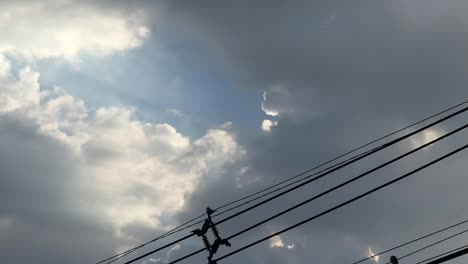 Gray-overcast-clouds-on-blue-sky-before-rain-or-storm.-Electrical-power-lines-pass-through-the-sky.