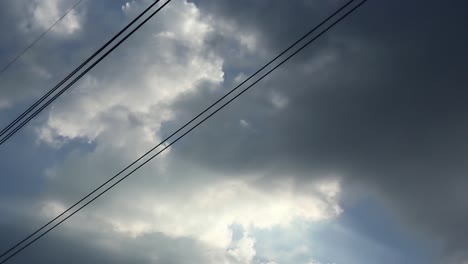 Gray-overcast-clouds-on-blue-sky-before-rain-or-storm.-Electrical-power-lines-pass-through-the-sky.