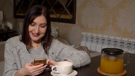 Mujer-en-un-café-en-una-mesa-bebiendo-té-y-hojear-a-través-de-una-cinta-de-las-redes-sociales