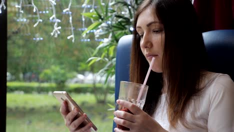 Hermosa-mujer-con-un-teléfono-en-un-café-mueve-vino-caliente