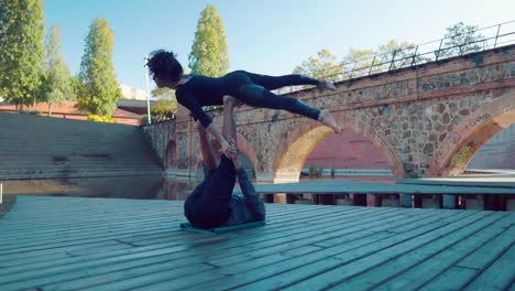 Schönes-paar-praktizieren-Acro-Yoga-am-Morgen