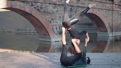 Schönes-paar-praktizieren-Acro-Yoga-am-Morgen