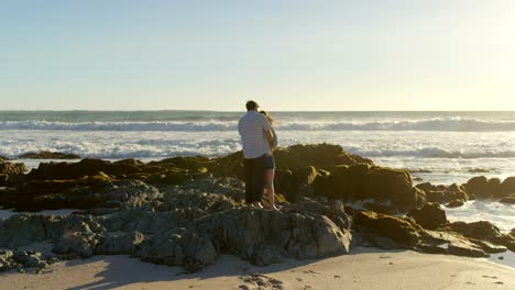 Couple-standing-on-rocky-shore-at-beach-4k