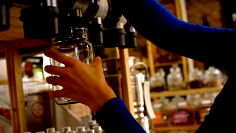 Close-up-of-woman-filling-grains-in-to-jar-from-vending-machine-4k