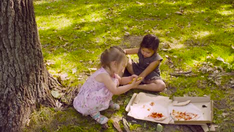 Zwei-Mädchen-im-Park-Pizza-essen.