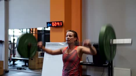 Mujer-fuerte-hace-ejercicio-de-levantamiento-de-pesas-durante-Cruz-entrenamiento-en-gimnasio