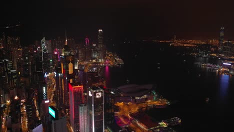 night-time-illuminated-hong-kong-cityscape-downtown-victoria-harbour-aerial-panorama-4k