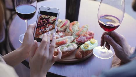 Comida-y-bebida-foto.-Mujer-mirando-fotos-en-la-pantalla-teléfono