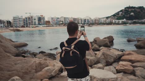 Tourist-taking-photos-of-a-sea-on-shore.