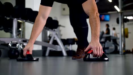 A-man-with-beautiful-muscles-wrung-out-from-the-floor-in-the-gym-4K-Slow-Mo