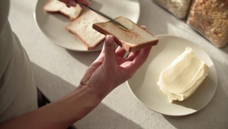 Toast-mit-Butter.-Hände,-die-Anwendung-von-Butter-auf-Brot-Closeup