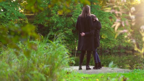 Woman-and-her-daughter-standing-near-the-pond.