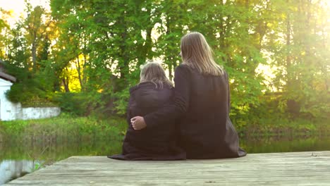 Frau-und-ihre-Tochter-sitzen-in-der-Nähe-des-Teiches.