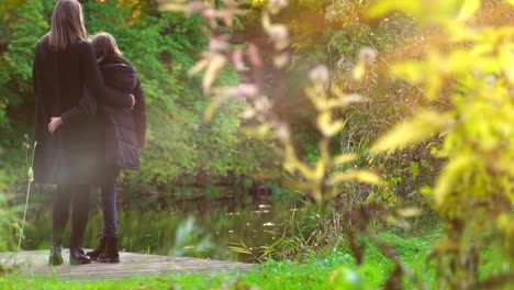 Woman-and-her-daughter-standing-near-the-pond.