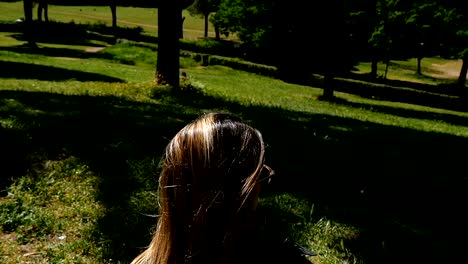 Traurige-nachdenkliche-blonde-Frau-sitzen-auf-dem-Rasen-im-Stadtpark