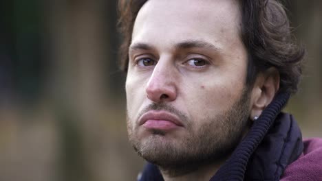 Close-up-on-sad-and-thoughtful-man-looks-at-the-camera,-outdoor