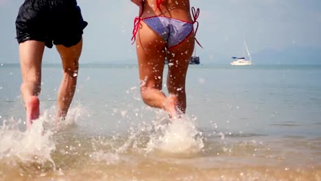 Young-joyful-couple-running-into-tropical-sea-enjoying-vacation-time-in-slow-motion.-1920x1080