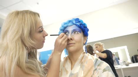 A-professional-make-up-artist-paints-on-the-eyelids-of-the-model.-Preparation-for-an-artistic-photo-shoot