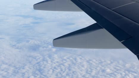 Blick-auf-die-Flügel-eines-Flugzeuges-im-Flug-über-schöne-Luft-Wolken