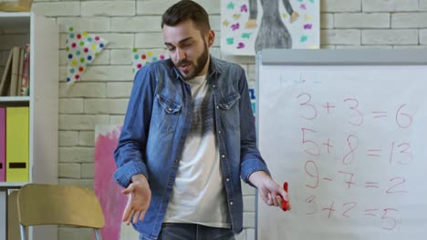 Male-Teacher-Writing-on-Whiteboard-at-Math-Lesson-in-Kindergarten