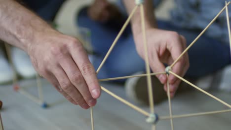 Hombres-manos-haciendo-construcción-con-palos-de-madera