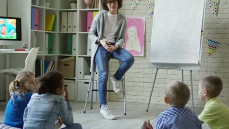 Little-Pupils-Listening-to-Female-Teacher-in-Kindergarten