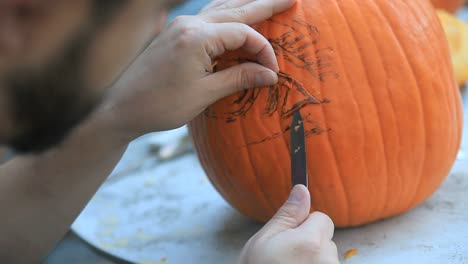 Man-using-knife-to-carve-Halloween-pumpkin