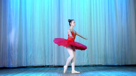 ballet-rehearsal,-on-the-stage-of-the-old-theater-hall.-Young-ballerina-in-red-ballet-tutu-and-pointe-shoes,-dances-elegantly-certain-ballet-motion,-pas-courru-,-tour-fouette