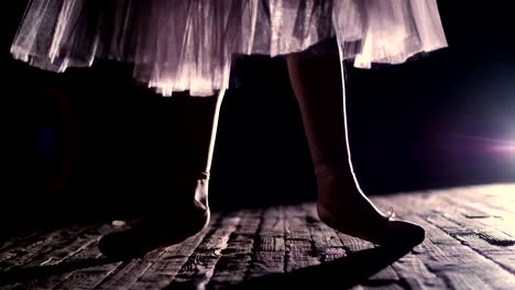 close-up,-in-rays-of-spotlight,-on-the-stage-of-the-old-theater-hall.-ballerina-in-white-ballet-skirt,-raises-on-toes-in-pointe-shoes,-performs-elegantly-a-certain-ballet-exercise,-relleve