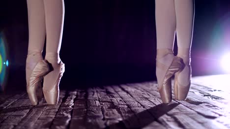 close-up,-in-rays-of-spotlight,-on-the-stage-of-the-old-theater-hall.-ballerinas-standing-on-toes-in-pointe-shoes,-performs-elegantly-a-certain-ballet-exercise,-pas-de-bourre-suivi