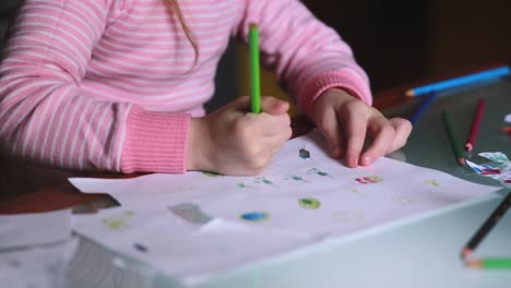 Primer-tiro-de-caucásico-lindo-niña-aprendiendo-a-dibujar-en-papel-con-un-lápiz-con-toda-la-mano-en-casa-tabla