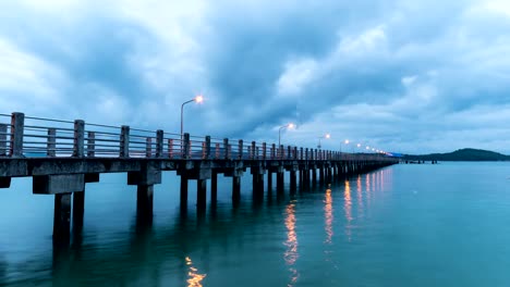 Timelapse-Wolken-bewegen-schnell-bei-Sonnenaufgang-oder-Sonnenuntergang-über-Meer-mit-Zement-Brücke-steht-im-Vordergrund