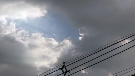 Gray-overcast-clouds-on-blue-sky-before-rain-or-storm.-Electrical-power-lines-pass-through-the-sky.