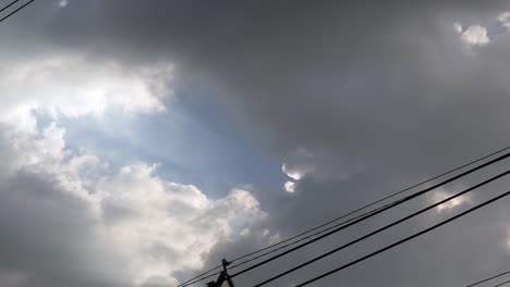 Gray-overcast-clouds-on-blue-sky-before-rain-or-storm.-Electrical-power-lines-pass-through-the-sky.