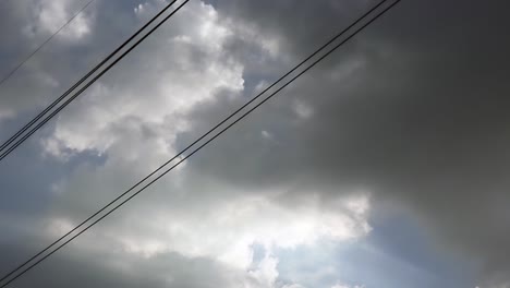 Gray-overcast-clouds-on-blue-sky-before-rain-or-storm.-Electrical-power-lines-pass-through-the-sky.