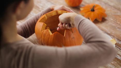 close-up-of-woman-carving-halloween-pumpkin