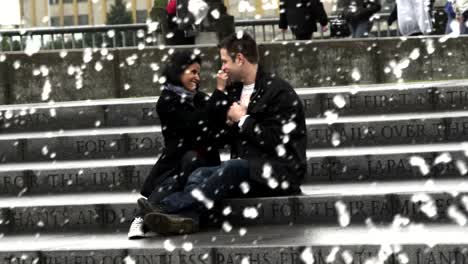 A-couple-sits-on-some-steps-in-front-of-a-fountain-while-holding-hands