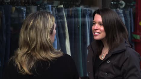 Two-girl-friends-go-window-shopping-and-look-at-jeans