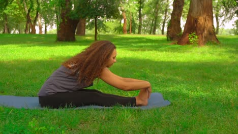 slim-woman-does-forward-bend-pose-in-park