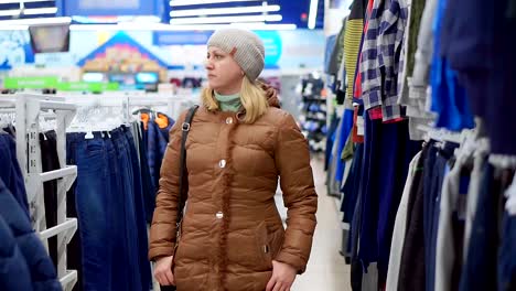 A-middle-aged-woman-in-a-winter-coat-and-a-hat-goes-to-a-children's-clothing-store.