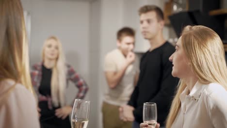 Young-people-with-glasses-of-champagne-talking-and-preparing-in-kitchen