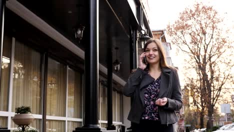 Attractive-caucasian-businesswoman-walking-on-the-street-on-the-office-building-background,-talking-on-the-phone.